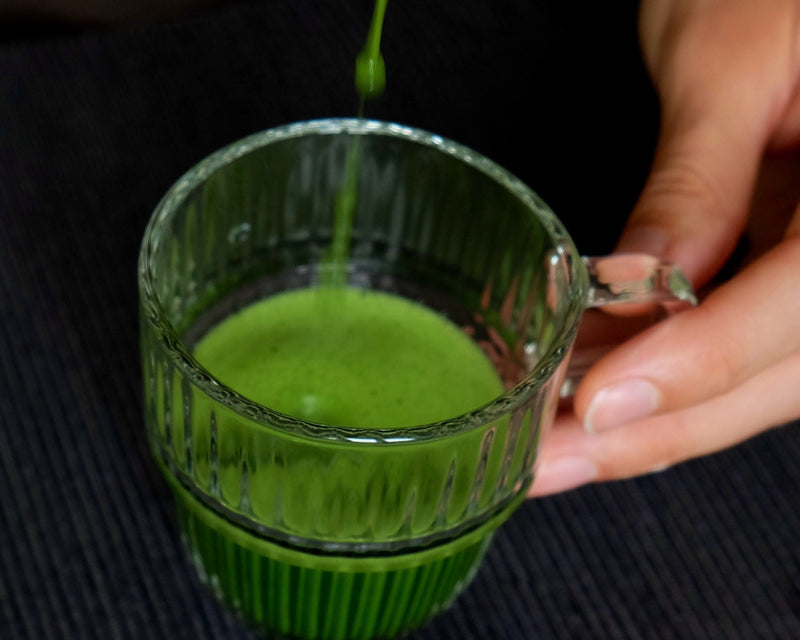 matcha being poured from a container into a glass.