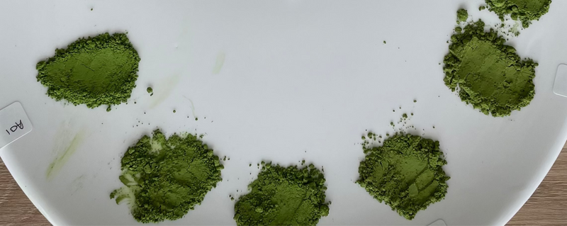 Circular white plate with matcha  samples and labels on a wooden surface