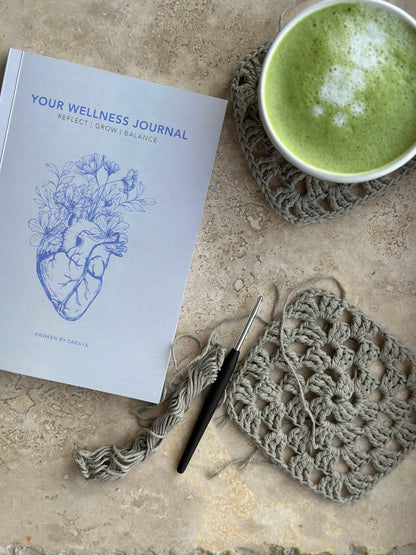 The awaken wellness journal with a crochet hook and crochet granny square and a matcha latte